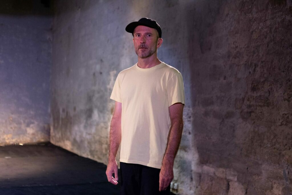 Homme en t-shirt blanc et casquette noire à l’Espace culturel Angonia,