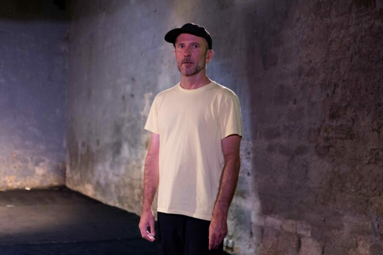 Homme en t-shirt blanc et casquette noire à l’Espace culturel Angonia,