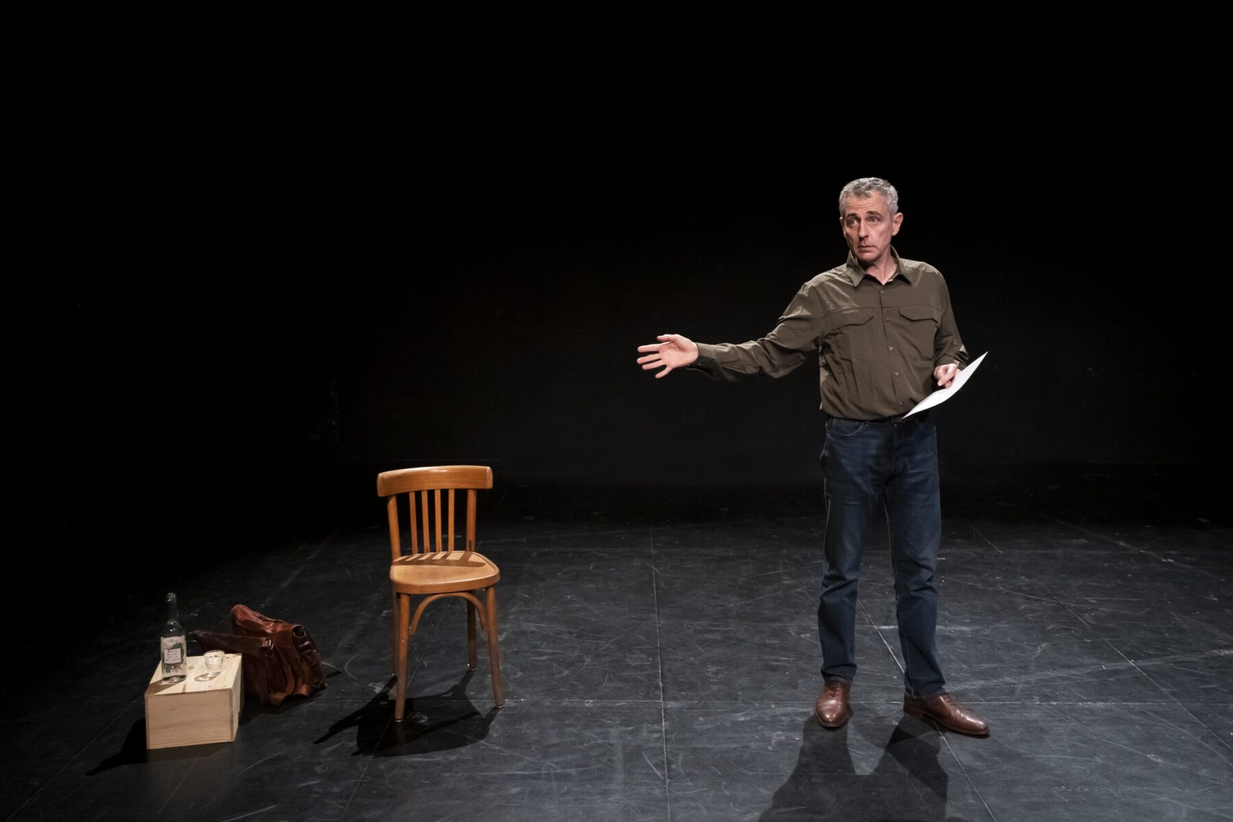 Homme sur scène tenant une feuille et faisant un geste de la main